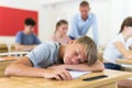 Tired bored teenage schoolboy sleeping at desk Royalty Free Stock Photo