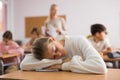 Tired bored teenage schoolgirl sleeping at desk closeup Royalty Free Stock Photo