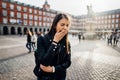 Tired bored woman yawning in main Plaza Major square of Madrid,Spain.Sightseeing female tourist covering moutht.Lack of slee Royalty Free Stock Photo