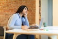 Tired boring teen indian girl student studying at home, sitting in front of laptop and looking away at free space