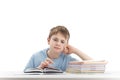 Tired boy doing homework at table and attentively reads book. Portrait of schoolboy at desk with stack of notebooks. White Royalty Free Stock Photo