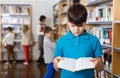 Tired boy looking for textbooks in library Royalty Free Stock Photo