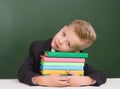 Tired boy lying on books in classroom Royalty Free Stock Photo