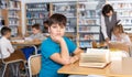 Tired boy reading textbooks in school library Royalty Free Stock Photo