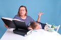 Tired boy schoolboy sleeping at a school desk and mom doing homework, blue background Royalty Free Stock Photo