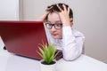 A tired boy, schoolboy in white formal shirt sitting by the table, desk with laptop and doing homework at home, e-learning and Royalty Free Stock Photo