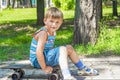 Tired boy with a scratched knee sits on a skateboard while resting Royalty Free Stock Photo