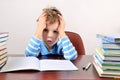 Tired boy sitting at a desk and holding hands to head Royalty Free Stock Photo