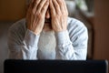 A tired, broken, resigned, preoccupied elderly man sits in front of a laptop, computer and covers his face with his hand. Royalty Free Stock Photo