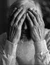 A tired, broken, resigned, preoccupied elderly man sits in front of a laptop, computer and covers his face with his hand. Royalty Free Stock Photo