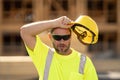 Tired builder, hard work concept. Builder with hardhat helmet on construction site. Construction builder worker in Royalty Free Stock Photo