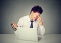 Tired business man rubbing eye sitting at table with laptop