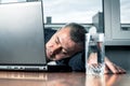 Tired business man sleeps near his laptop. Young bearded tired man sleeping on office table. Work routine concept Royalty Free Stock Photo