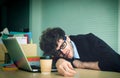 Tired business man taking a nap on working desk in office with computer laptop and coffee for office overworked concept Royalty Free Stock Photo