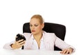 Tired business woman sitting behind the desk and holding alarm clock Royalty Free Stock Photo