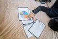 Tired businessman lying on the bed with a pile of graph papers on his hand that was in front of him Royalty Free Stock Photo