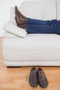 Tired businessman lying on sofa with shoes off Royalty Free Stock Photo