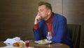 Tired businessman sitting at table and does not want to eat unappetizing dishes