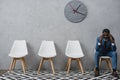 Tired businessman sitting in a waiting room and touching head with hands, having Royalty Free Stock Photo