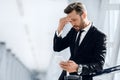 Tired businessman standing by window in airport, using phone Royalty Free Stock Photo