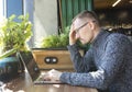 Tired businessman is trying to solve problem with work. A Man sits with serious face in front of computer. Royalty Free Stock Photo