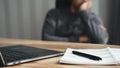 Tired businessman working on laptop with notepad and pen, resting head on hand, doing work overtime, stressed and bored Royalty Free Stock Photo