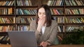 Tired businesswoman in brown jacket types on grey laptop Royalty Free Stock Photo