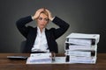 Tired Businesswoman With Hands On Head At Desk Royalty Free Stock Photo