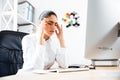 Tired businesswoman having a headache while sitting at the desk Royalty Free Stock Photo