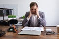 tired caucasian businessman sitting in front of documents in the office massaging his head temples Royalty Free Stock Photo