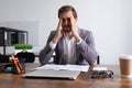 tired caucasian businessman sitting at his desk massaging his head with his hands Royalty Free Stock Photo