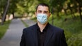 Tired caucasian businessman takes off medical face mask protective respirator exhausted man guy stands in city park Royalty Free Stock Photo