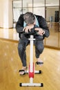 Tired Caucasian man sleeping on a spin bike Royalty Free Stock Photo