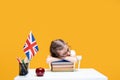 Tired caucasian schoolgirl sitting at the desk and sleeping. English lesson Great Britain flag Royalty Free Stock Photo