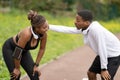 Tired cheerful young african american couple in sportswear having rest after jogging in park Royalty Free Stock Photo