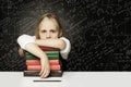 Tired child with books thinking on chalkboard with formulas