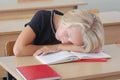 Tired child schoolgirl sleeps during a lesson at the desk in a classroom Royalty Free Stock Photo