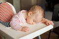 Tired child sleeping in highchair after the lunch. Cute baby girllying his face on the table tray. Royalty Free Stock Photo