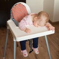 Tired child sleeping in highchair after the lunch. Cute baby girllying his face on the table tray. Royalty Free Stock Photo