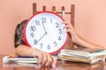 Tired child sleeping and holding a clock