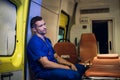 Tired corpsman in uniform sits inside the ambulance car