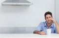 Man sitting at kitchen counter supporting head with hand while holding white mug, copy space Royalty Free Stock Photo
