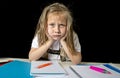 Tired cute junior schoolgirl with blond hair sitting in stress working doing homework looking bored