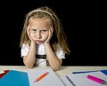 Tired cute junior schoolgirl with blond hair sitting in stress working doing homework looking bored