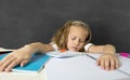 Tired cute junior schoolgirl with blond hair sitting in stress working doing homework looking bored