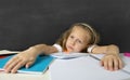 Tired cute junior schoolgirl with blond hair sitting in stress working doing homework looking bored