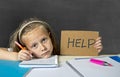 Tired cute junior schoolgirl with blond hair sitting in stress working doing homework looking bored