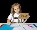 Tired cute junior schoolgirl with blond hair sitting in stress working doing homework looking bored