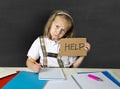 Tired cute junior schoolgirl with blond hair sitting in stress working doing homework looking bored