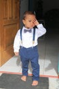 Tired toddler boy in shirt with bowtie standing in door